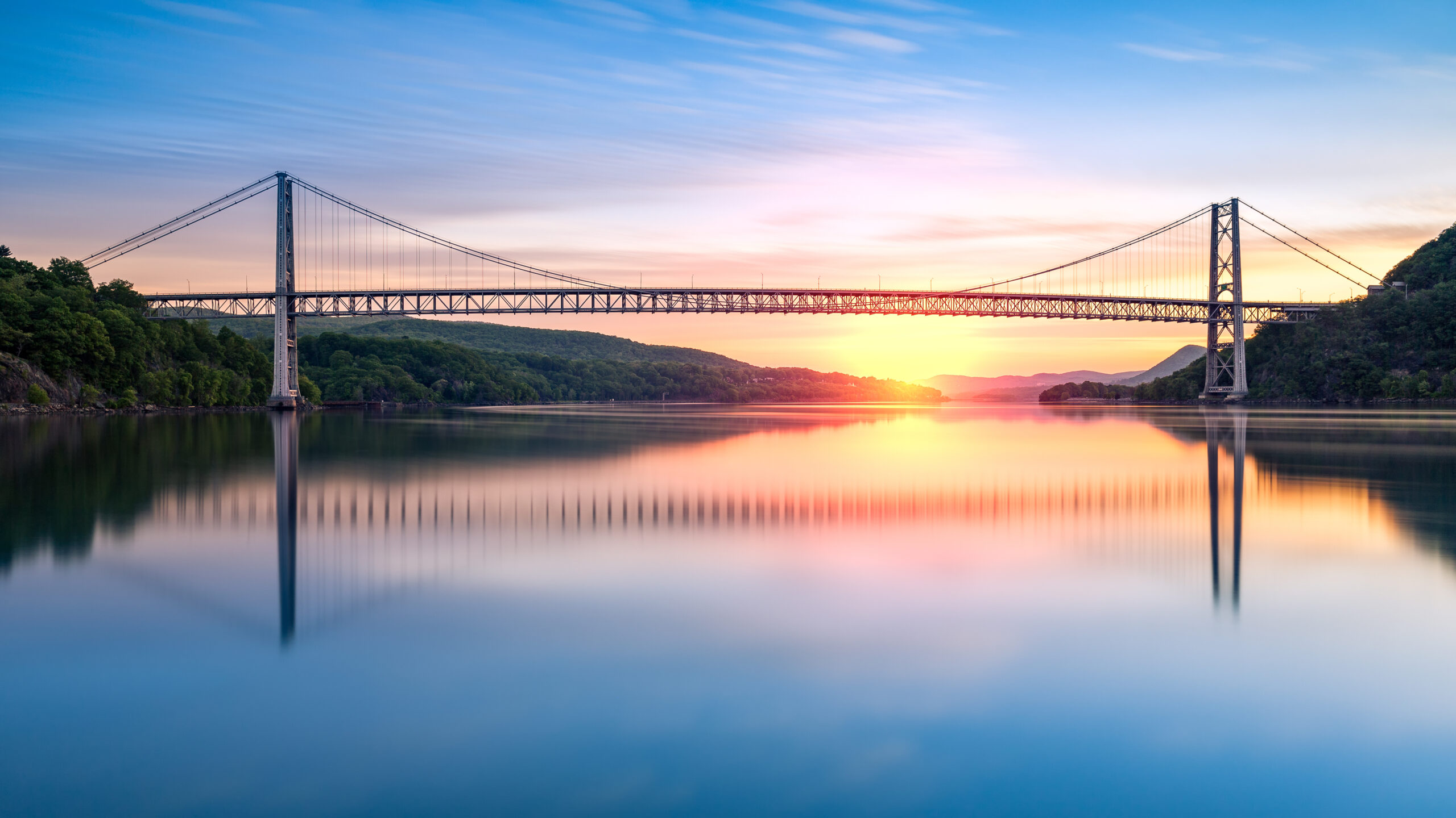 Bear Mountain Bridge at sunrise (long exposure). Bear Mountain Bridge is a toll suspension bridge in New York State, carrying U.S. Highways 202 and 6 across the Hudson River