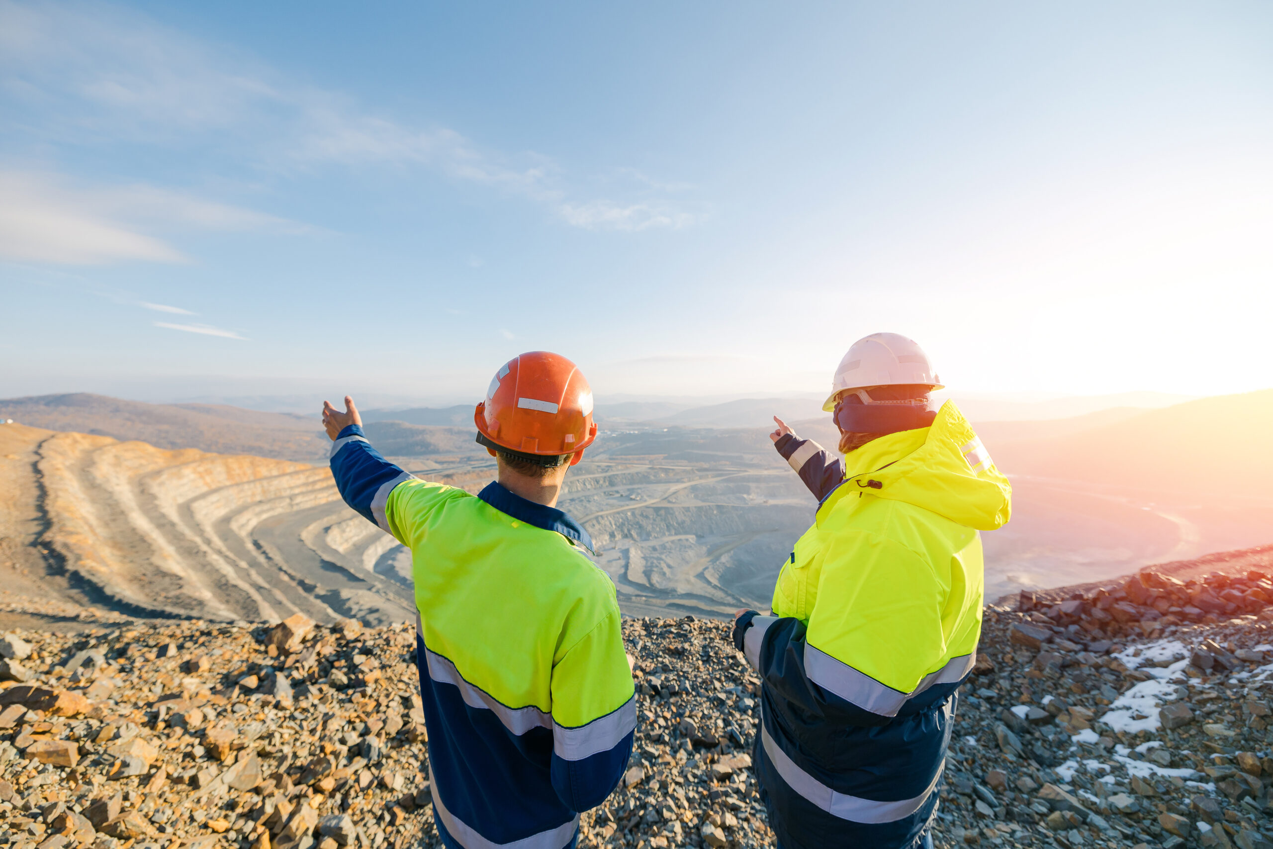 Mining Engineers worker and loss control representative on Open Pit Quarry overlooking ore mine, back view.