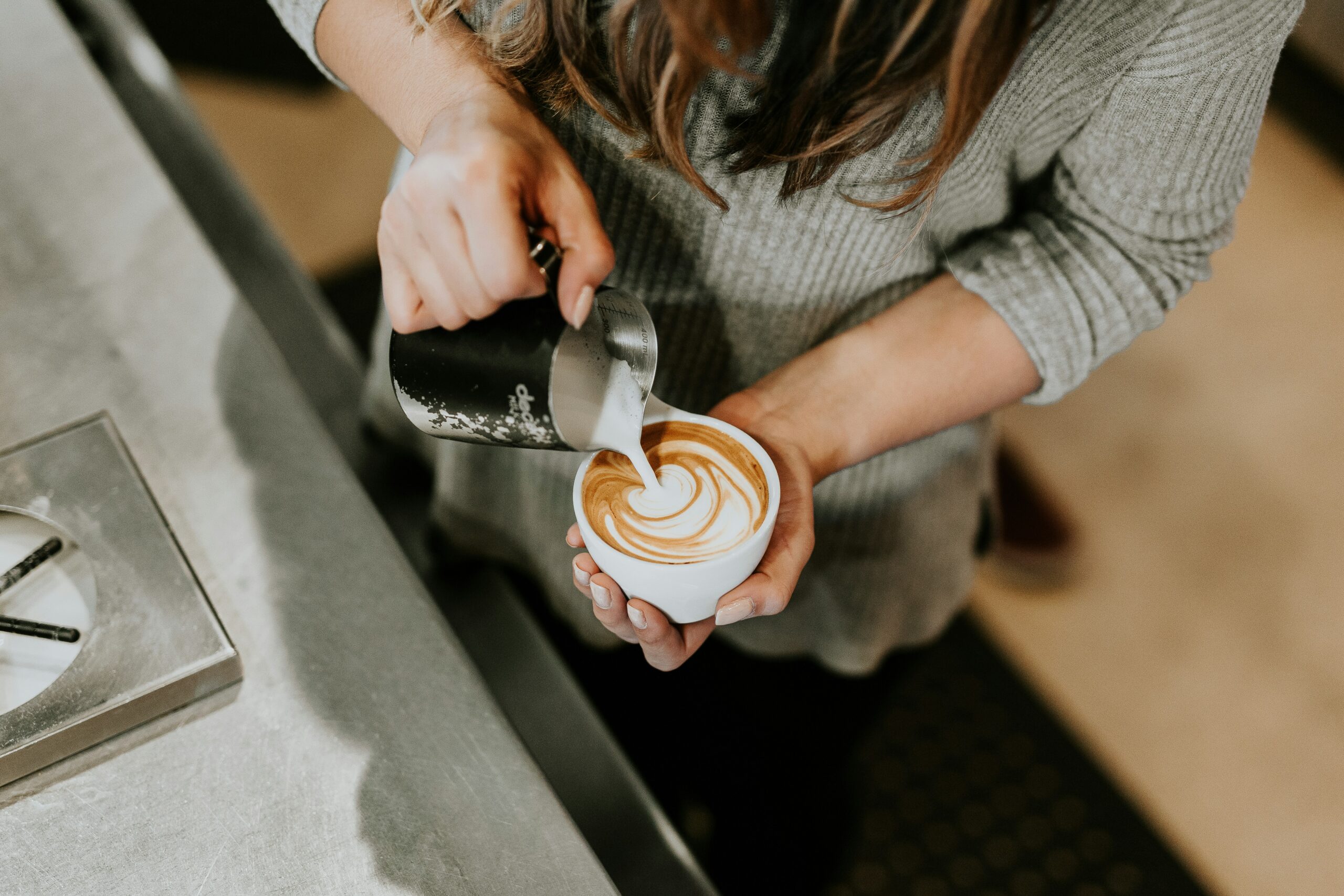 Woman making latte art in a cafe.